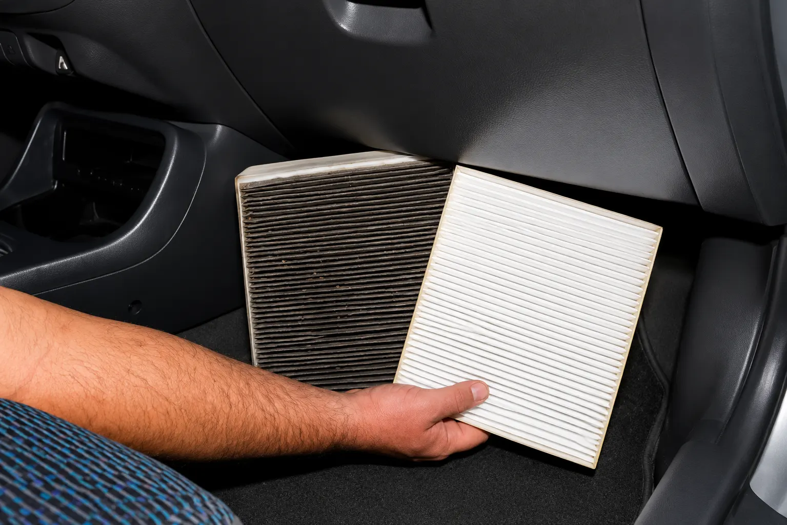 Técnico realizando el cambio del filtro de cabina para mejorar el rendimiento del aire acondicionado automotriz.